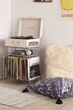 a record player sitting on top of a table next to a pillow and some records