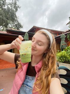 a woman drinking from a green cup with her eyes closed