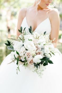 a bride holding a bouquet of white and pink flowers