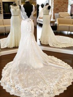 the back of a wedding dress on display in front of a mirror with mannequins