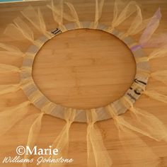 a wooden table topped with a white and yellow tulle wreath on top of it