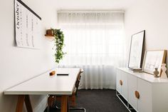 a room with a white table and some plants on the wall next to it in front of a window