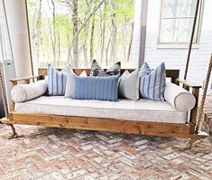 a porch swing with pillows on it