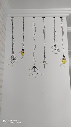 several light bulbs hanging from the ceiling in a room with white walls and black wires