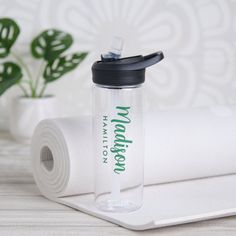 a clear water bottle sitting next to a roll of toilet paper on top of a table