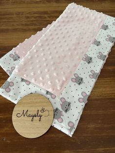 three pieces of pink and white fabric on top of a wooden table next to a round object