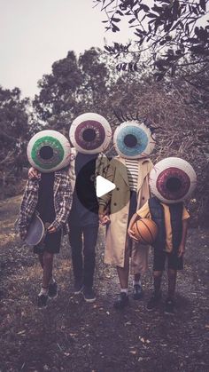 a group of people standing next to each other in front of trees with frisbees on their heads