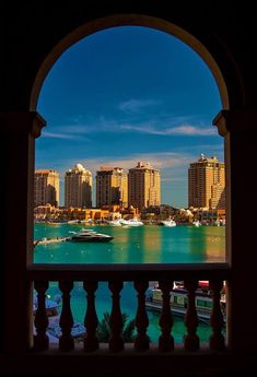 the view from an arched window looking at boats in the water and buildings on the other side