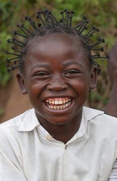 a smiling young boy with dreadlocks on his head and white shirt in front of him