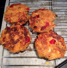 four crab cakes sitting on top of a metal rack next to an oven mitt