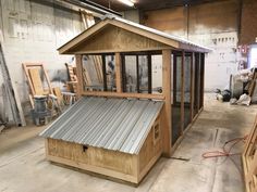 a small wooden building sitting inside of a garage next to other wood and metal structures