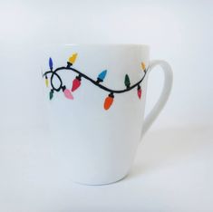 a white coffee cup decorated with christmas lights