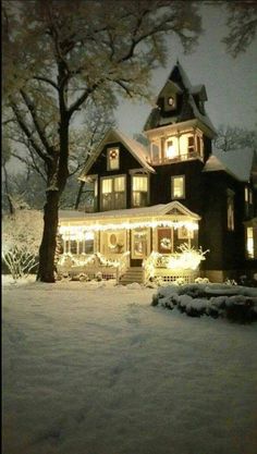 a large house with christmas lights on it's windows and trees in the snow