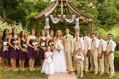 a group of people standing next to each other in front of a wooden gazebo