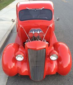 an old red car is parked on the side of the road