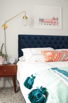 a bedroom with a blue headboard and colorful pillows on the bedspread next to a night stand