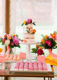 a table topped with lots of cakes and donuts covered in frosting next to flowers