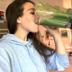 a woman drinking out of a green cup