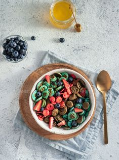 a bowl filled with cereal and blueberries on top of a table next to a spoon