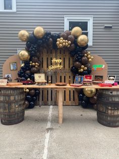 a table that has some balloons on it and wine barrels in front of the table