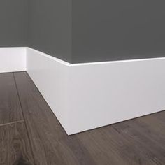 an empty room with wood flooring and white trim on the walls, in front of a gray wall