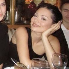 two women sitting next to each other at a table with wine glasses and food in front of them