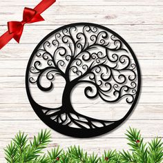 a metal tree ornament with a red ribbon around it on a wooden background