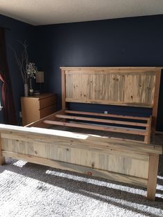 a wooden bed frame in a bedroom with blue walls and carpeted flooring area