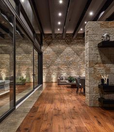 an empty room with wood floors and stone walls, along with glass doors leading to the outside