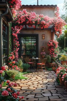 a patio covered in pink flowers next to a table with chairs and potted plants