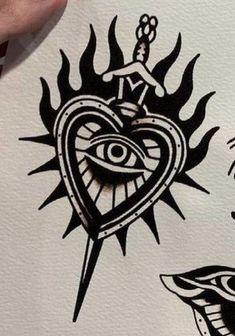 someone is drawing on paper with black ink and has an eye in the heart, two hands holding scissors