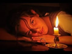 a woman laying down next to a candle