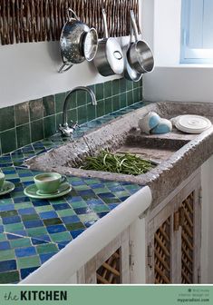 a kitchen sink with pots and pans hanging on the wall next to it's counter