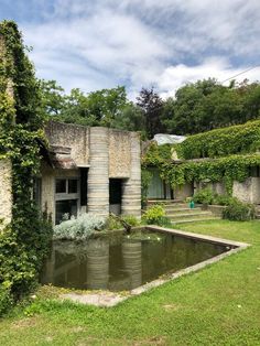 an old building with a pond in the middle and ivy growing on it's sides