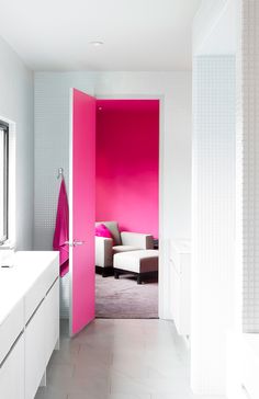 an open door leading to a bathroom with pink paint on the walls and white furniture