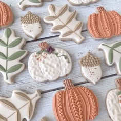 some decorated cookies are laying on a white wooden surface with leaves and acorns