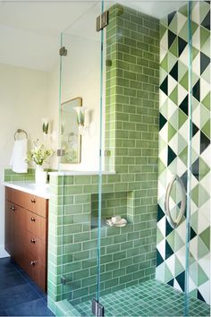 a bathroom with green tiles on the walls and floor, along with a walk in shower