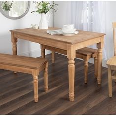 a wooden table with two chairs and a bench in front of it on a hard wood floor