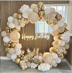 a white and gold balloon wreath with happy birthday written on it