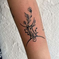 a black and white photo of a flower tattoo on the left arm, with vines growing out of it