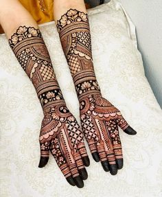 two hands with henna tattoos sitting on top of a bed