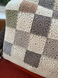 a crocheted blanket sitting on top of a wooden chair next to a window