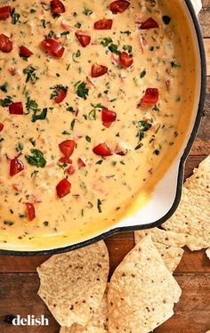 a pan filled with dip and tortilla chips on top of a wooden table