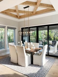 the dining room table is surrounded by white chairs and chandelier with candles on it