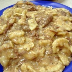 a blue plate topped with macaroni and cheese covered in gravy on top of a table