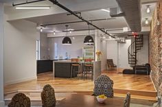 an open living room and kitchen area with hardwood floors, exposed ceilings, and brick walls