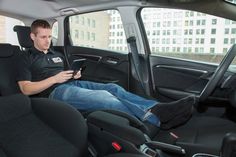 a man sitting in the back seat of a car looking at his cell phone