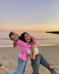 two young women hugging each other on the beach