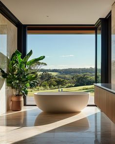 a large bathtub sitting in the middle of a bathroom next to a window with a view