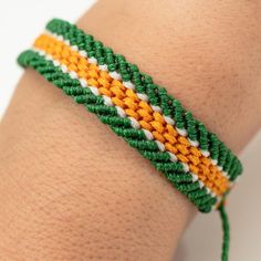 a close up of a person's arm wearing a bracelet with green, yellow and white beads